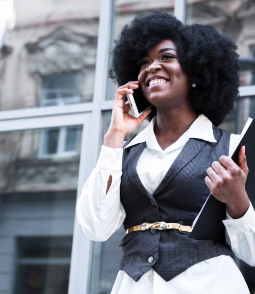 smiling-young-african-businesswoman-talking-mobile-phone-front-glass-door